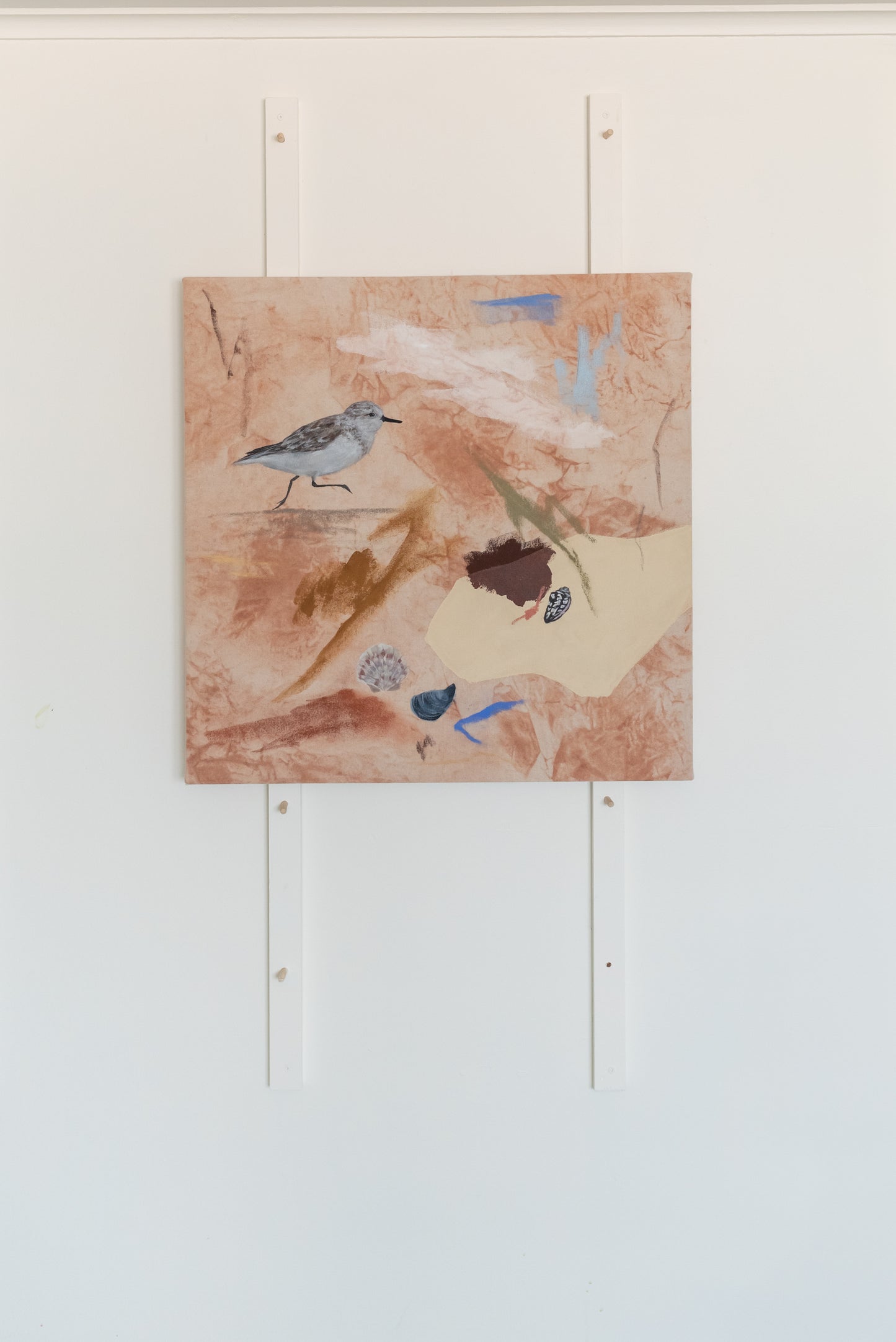 Coastal-inspired acrylic abstract painting featuring a sandpiper and various shells, displayed on a white studio wall.