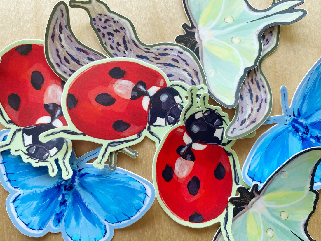 A messy pile of bug stickers including ladybugs, leopard slugs, luna moths, and blue butterflies.